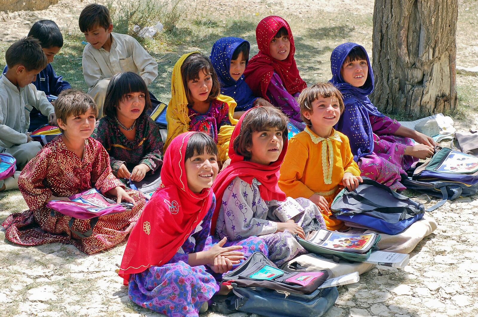 Schoolchildren sit in a section of a school in Bamozai, near Gardez, Paktya Province, Afghanistan. The school has no building; classes are held outdoors in the shade of an orchard.